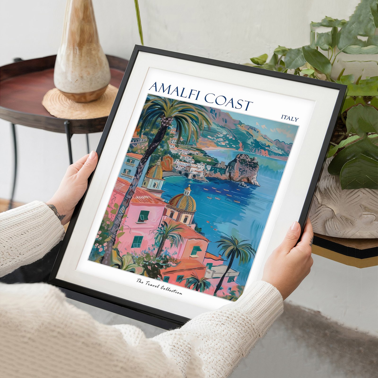 Hands holding a framed Amalfi Coast travel poster